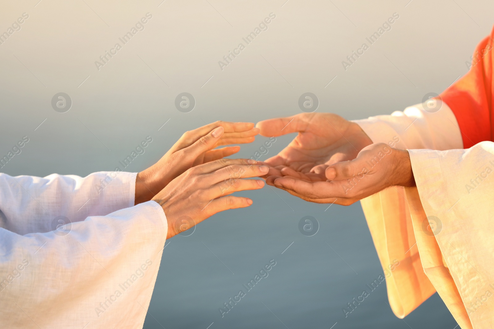 Photo of Woman reaching for Jesus Christ's hands near water outdoors, closeup