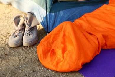 Photo of Sleeping bag and boots near tent on beach