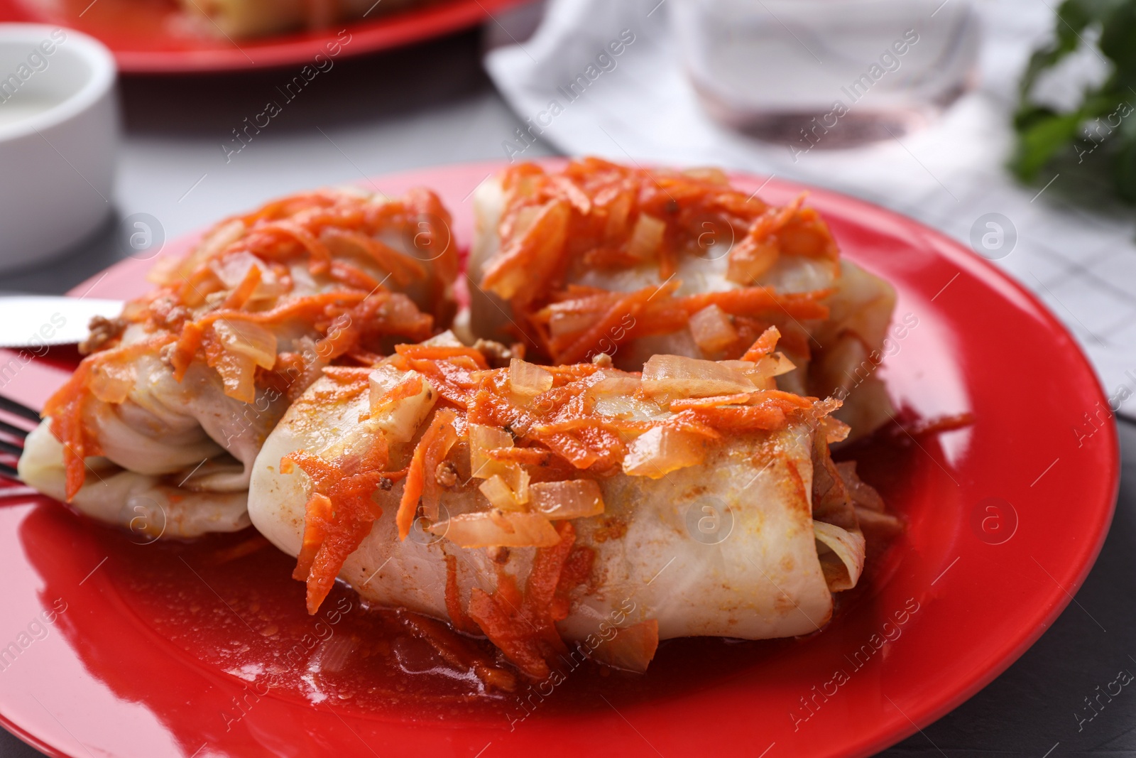 Photo of Delicious cabbage rolls served on red plate, closeup