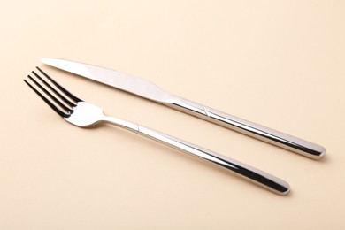 Stylish cutlery. Silver knife and fork on beige background