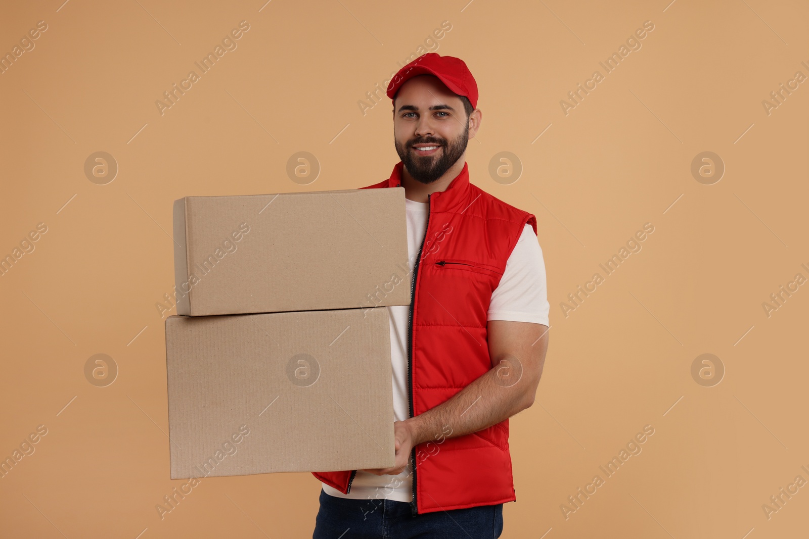 Photo of Happy young courier with parcels on light brown background