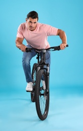 Photo of Handsome young man with modern bicycle on light blue background