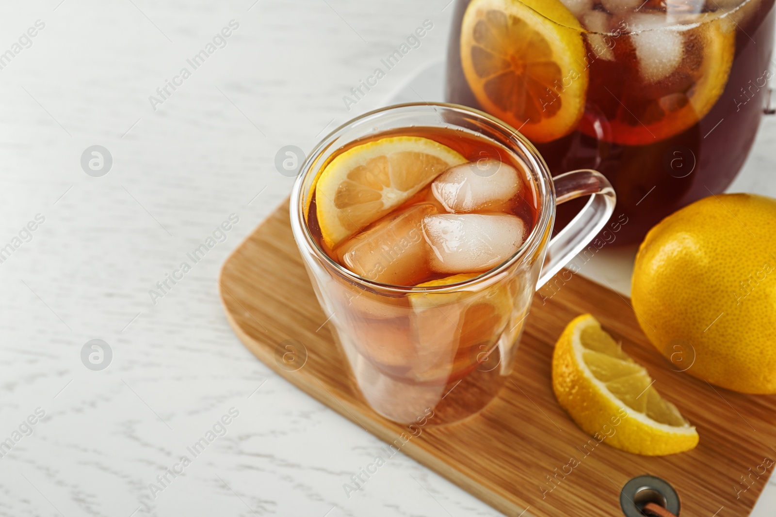 Photo of Cup and jug of refreshing iced tea on white table