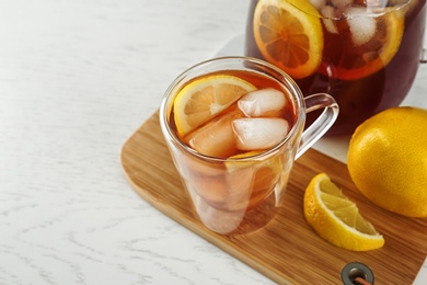 Cup and jug of refreshing iced tea on white table