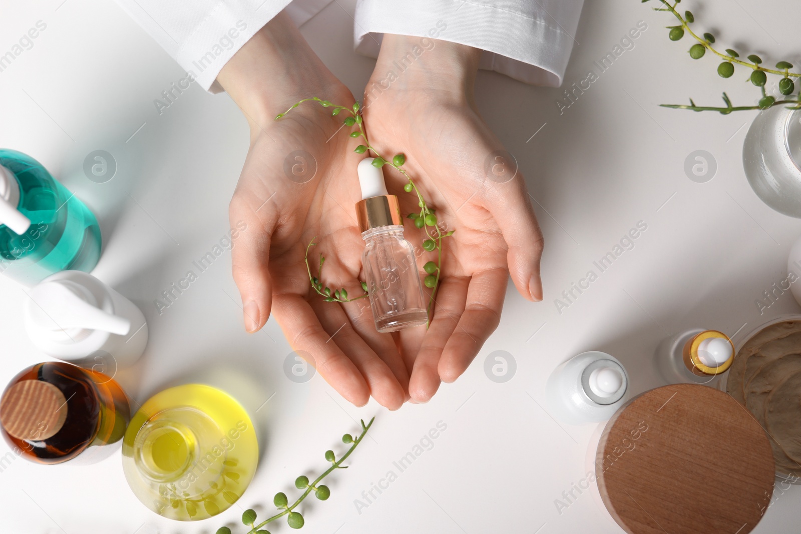 Photo of Dermatologist with bottle of essential oil at white table, top view. Development and testing