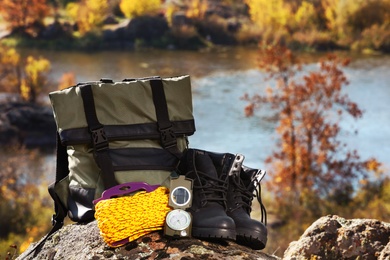 Photo of Set of camping equipment on rock outdoors. Space for text