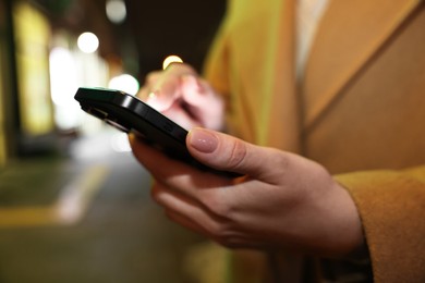 Woman using smartphone on night city street, closeup