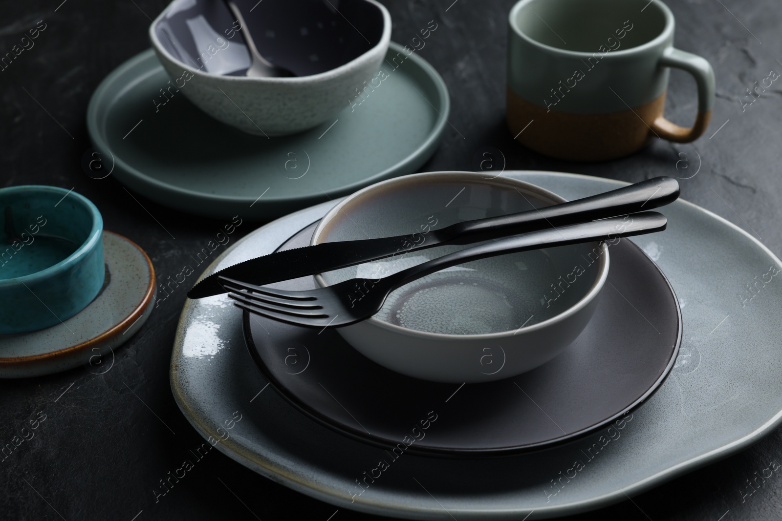 Photo of Set of clean tableware on black table