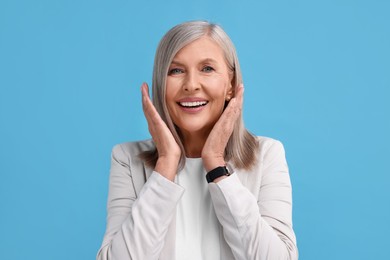 Portrait of emotional middle aged woman on light blue background