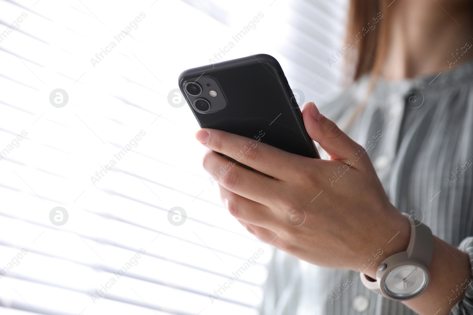 Photo of MYKOLAIV, UKRAINE - MARCH 16, 2020: Woman holding iPhone 11 Black indoors, closeup