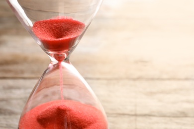 Hourglass with flowing sand on table, closeup. Time management