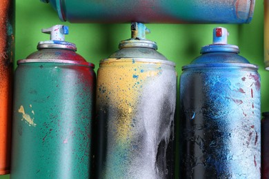 Photo of Many spray paint cans on green background, flat lay