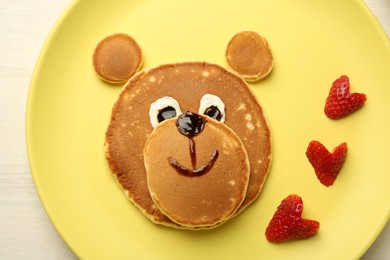 Photo of Creative serving for kids. Plate with strawberries, cute bear made of pancakes on table, top view