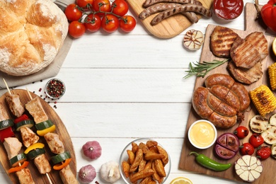 Photo of Frame of barbecued meat and vegetables on white wooden table, flat lay. Space for text