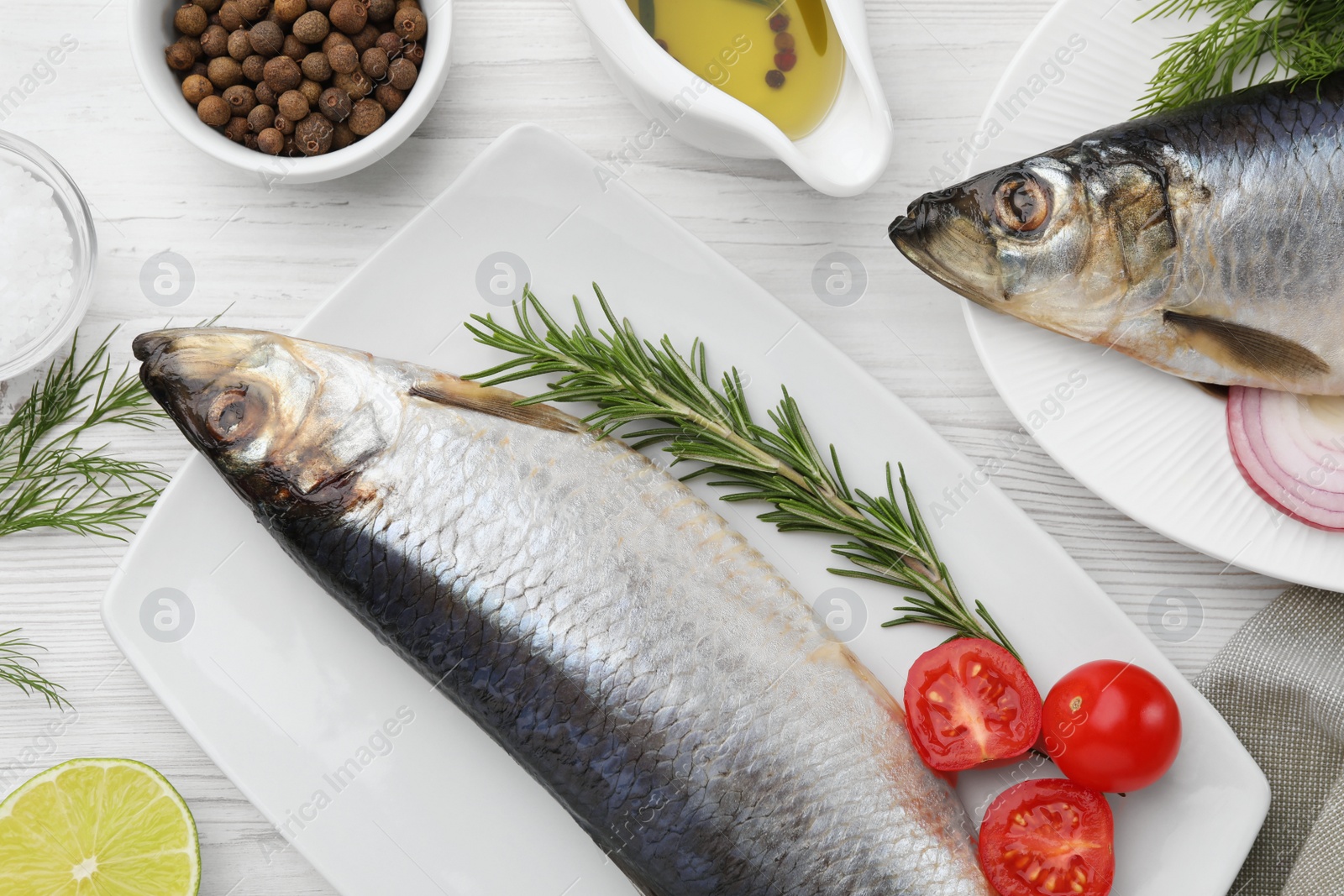 Photo of Delicious salted herrings and ingredients on white wooden table, flat lay