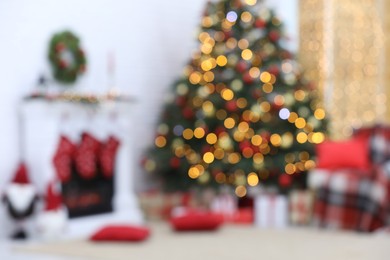 Blurred view of cosy room with tree and fireplace decorated for Christmas, bokeh effect. Interior design