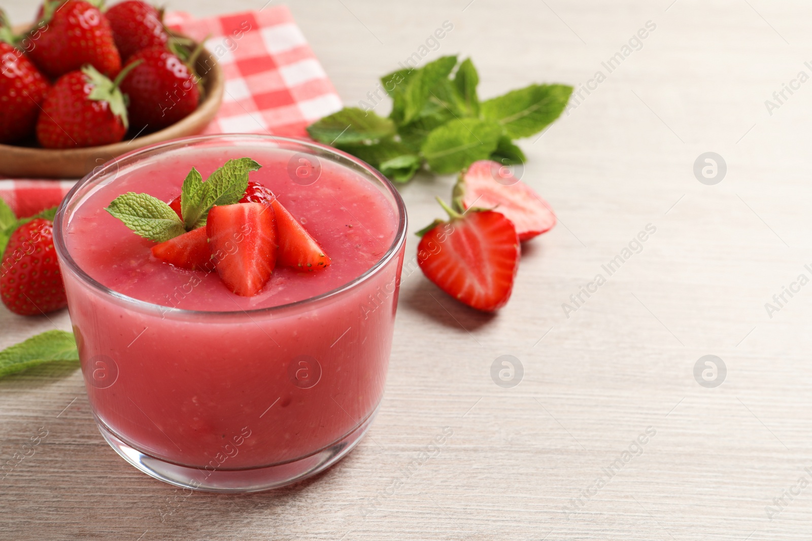 Photo of Delicious strawberry mousse with mint on white wooden table, space for text