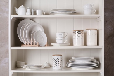 Stylish storage stand with different ceramic dishware at home