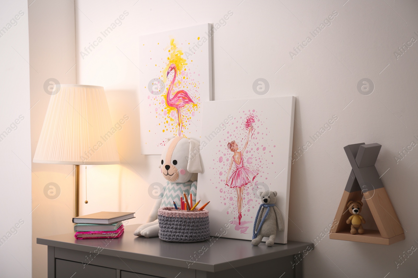 Photo of Pictures and stationery with toys on chest of drawers in children's room. Interior design