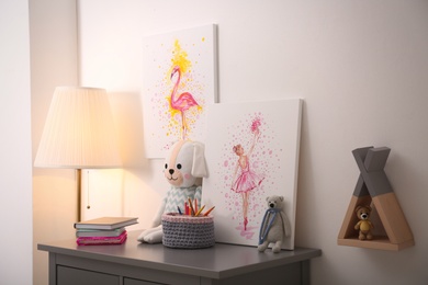 Pictures and stationery with toys on chest of drawers in children's room. Interior design