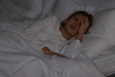 Little girl suffering from headache in bed at night