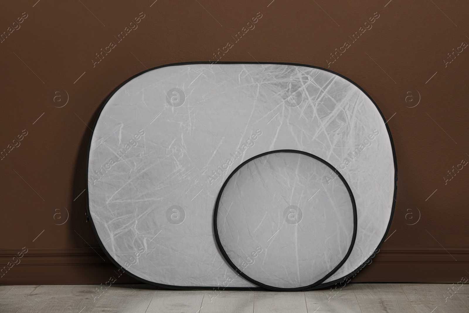 Photo of Studio reflectors near brown wall in room. Professional photographer's equipment