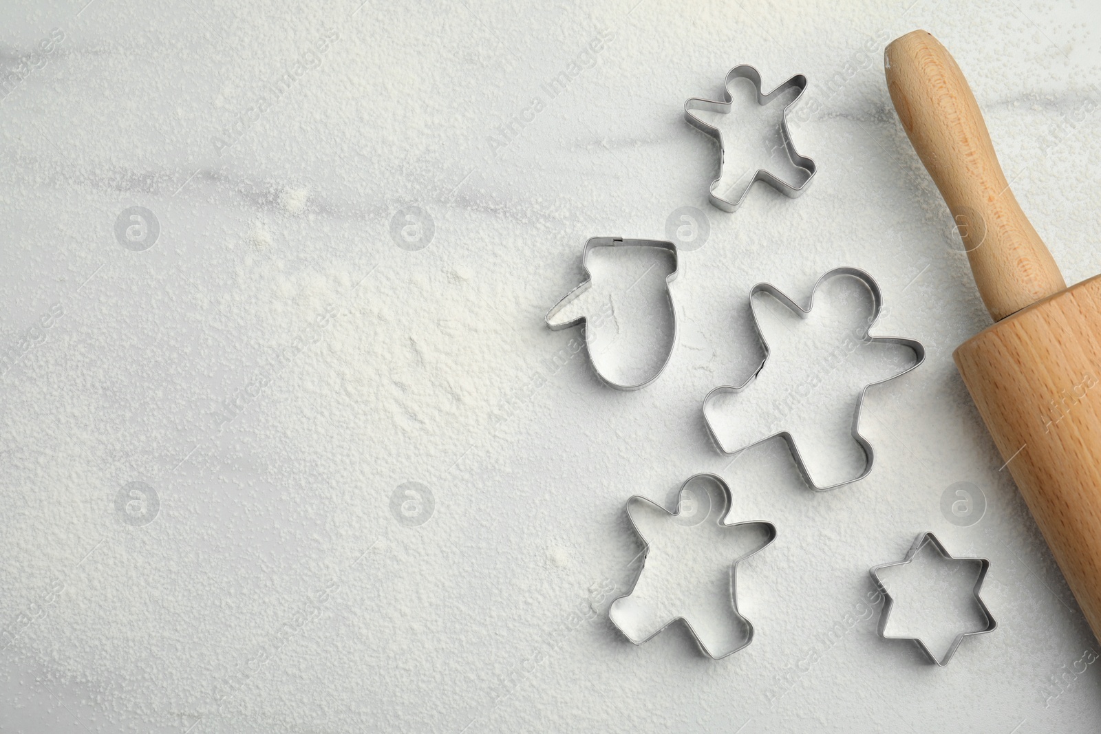 Photo of Cookie cutters, rolling pin and flour on white marble table, flat lay. Space for text
