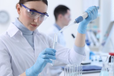 Photo of Scientist dripping sample into test tube in laboratory, selective focus