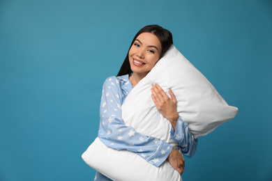 Photo of Beautiful Asian woman with pillow on blue background. Bedtime