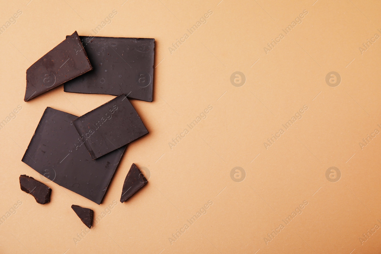 Photo of Broken chocolate bar on brown background, flat lay. Space for text