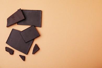 Broken chocolate bar on brown background, flat lay. Space for text