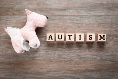 Photo of Toy and cubes with word "Autism" on wooden background
