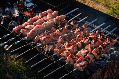 Photo of Cooking tasty kebab on metal skewers outdoors