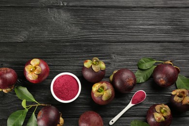 Photo of Purple mangosteen powder and fruits on black wooden table, flat lay. Space for text