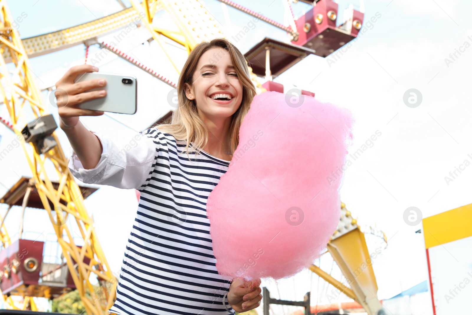 Photo of Attractive woman taking selfie with cotton candy in amusement park