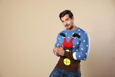 Photo of Portrait of happy man in Christmas sweater on beige background