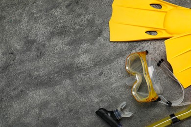 Photo of Sports equipment. Flippers, diving mask and snorkel on grey textured table, flat lay. Space for text