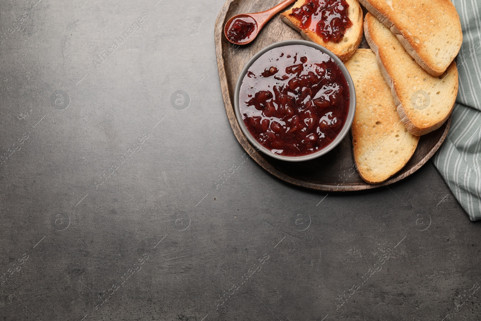 Photo of Toasts with delicious gooseberry jam on grey table, top view. Space for text