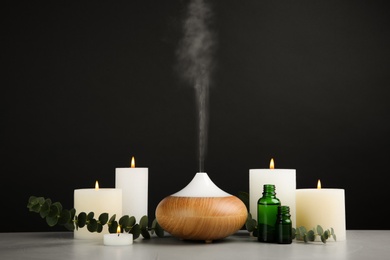 Photo of Composition with essential oils diffuser on table against black background. Space for text