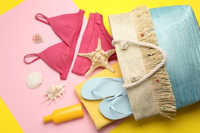 Stylish bag with beach accessories on color background, flat lay