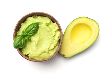 Bowl with guacamole and ripe avocado on white background, top view