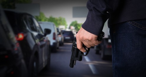 Image of Man with gun near cars outdoors, closeup