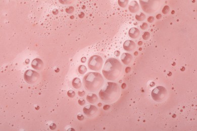 Tasty pink smoothie with bubbles as background, closeup