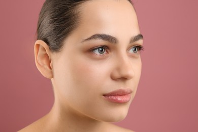 Young woman with perfect eyebrows on pink background