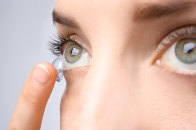 Young woman putting contact lens in her eye, closeup