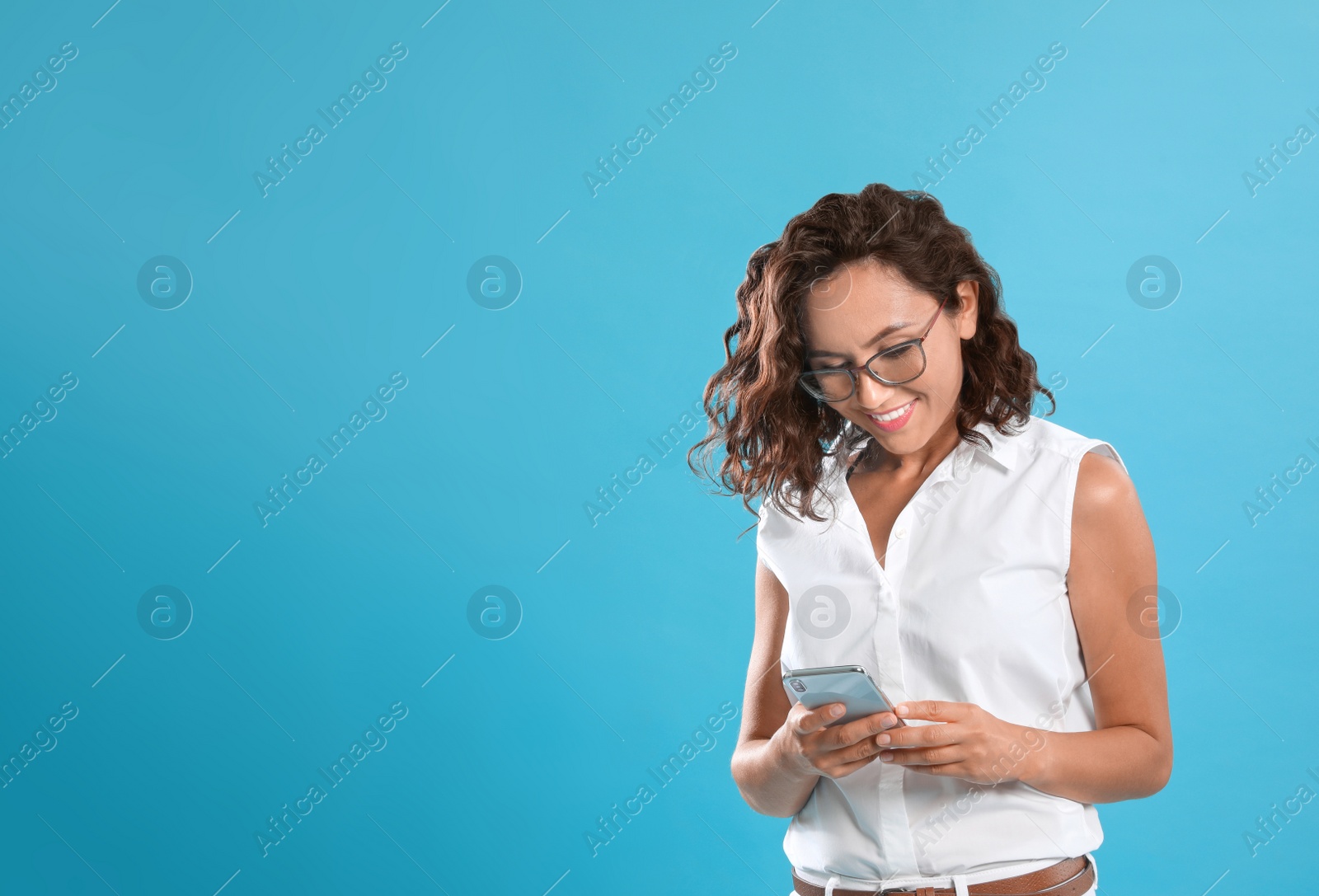 Photo of Happy young woman using smartphone on blue background. Space for text