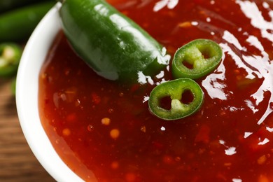 Photo of Spicy chili sauce in bowl on table, closeup