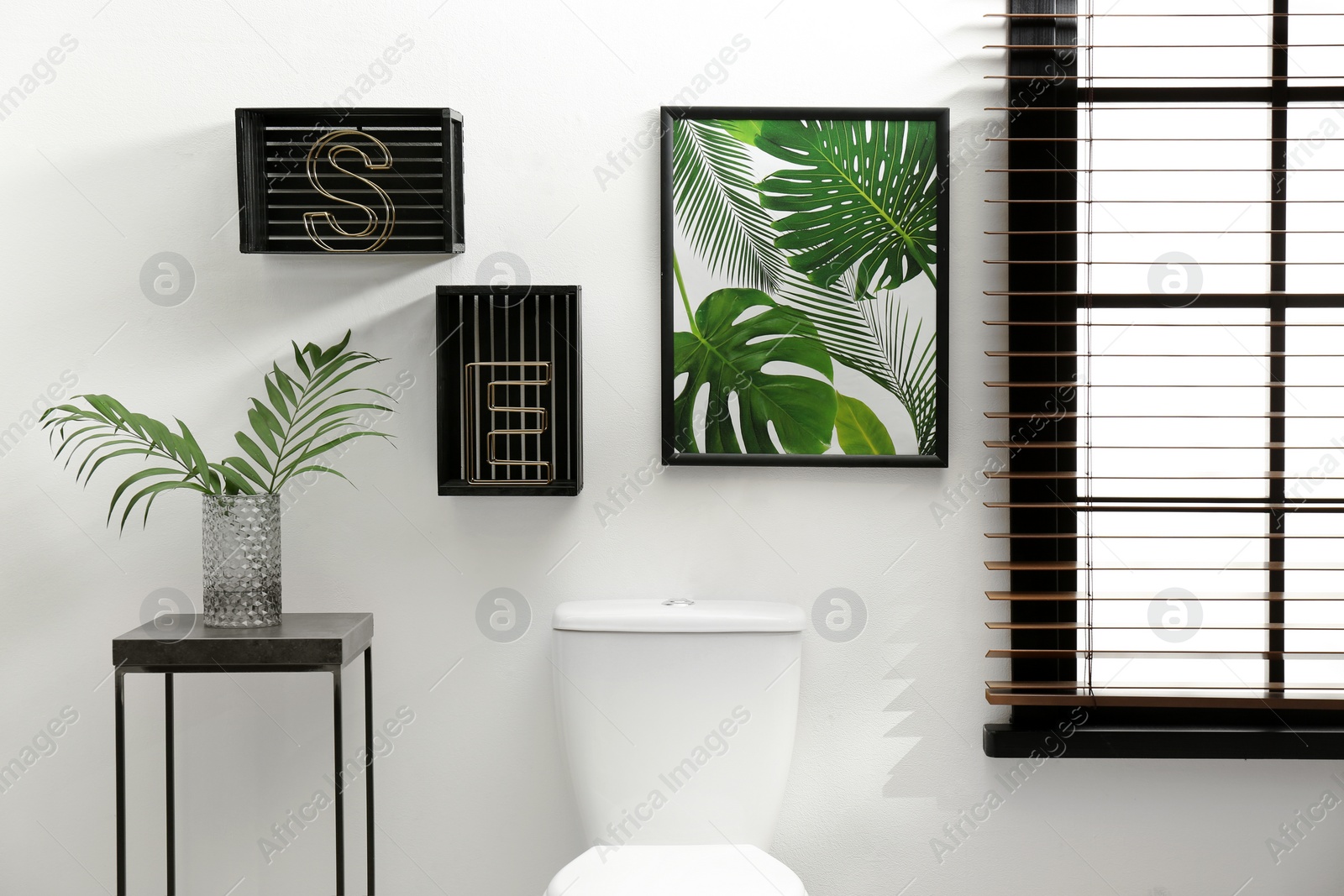 Photo of Table with vase and shelves near toilet bowl in restroom interior