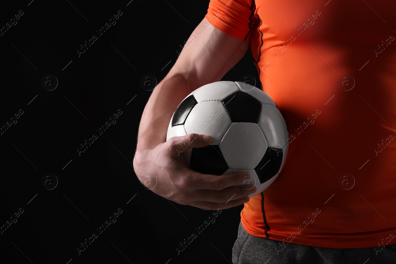 Photo of Athletic man with soccer ball on black background, closeup. Space for text