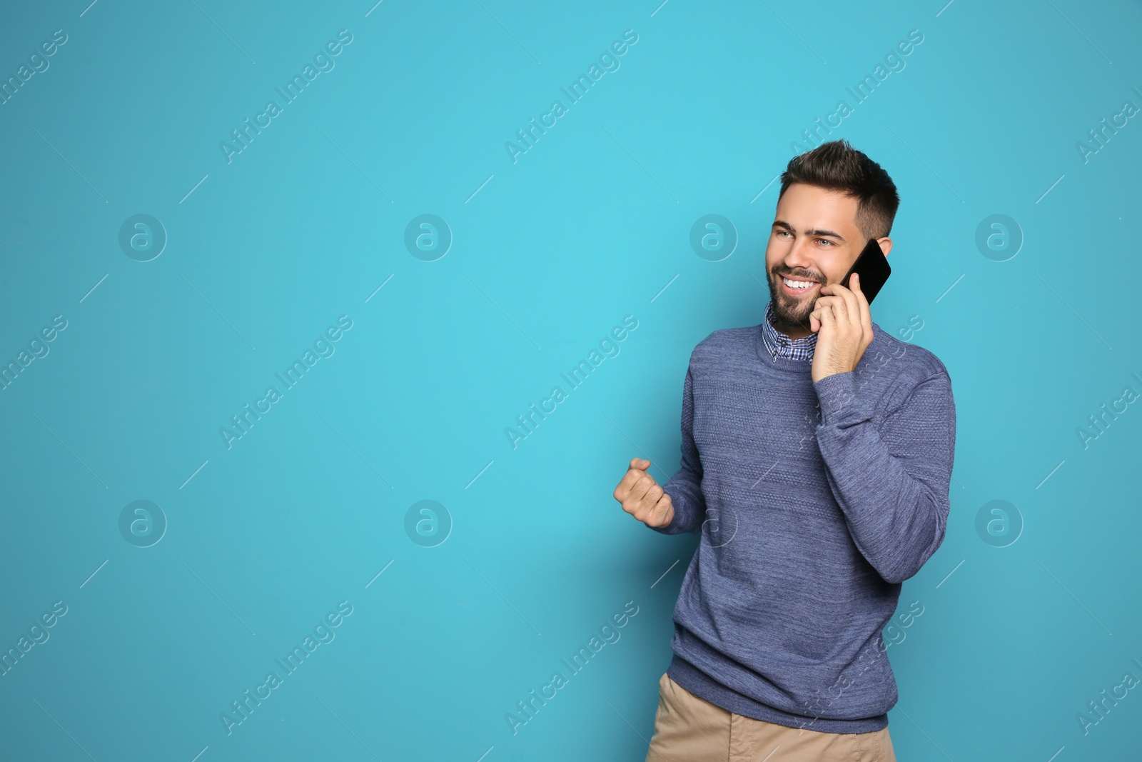 Photo of Happy young man with smartphone celebrating victory on color background. Space for text